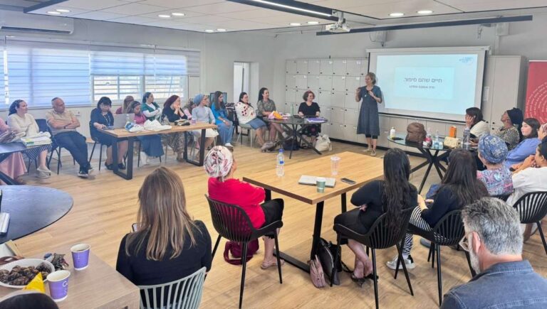 מרצה עומדת ומנחה קבוצת נשים במפגש והרצאה העוסקים בשיח, חיזוק פנימי ותהליכים ערכיים במסגרת הקומה הישראלית