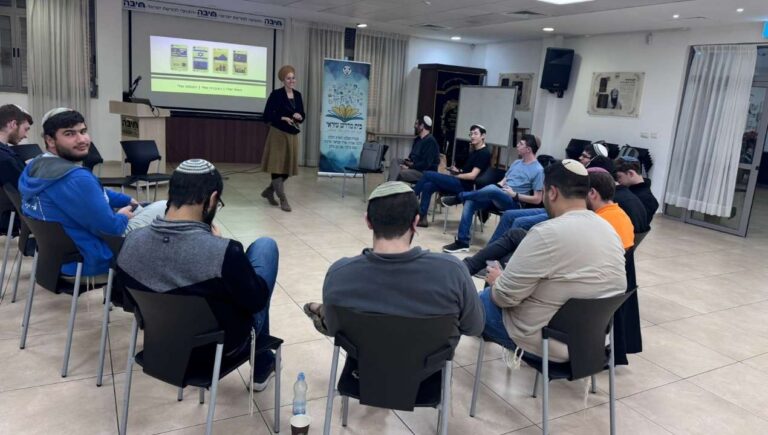 מנחה עומדת ומובילה מעגל שיח עם קבוצת צעירים במפגש חינוכי־ערכי, כחלק מפעילות הקומה הישראלית