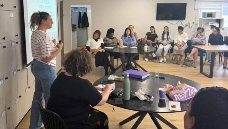 מנחה עומדת ומובילה שיח קבוצתי במפגש למידה והנחיה עם נשים, במסגרת פעילות הקומה הישראלית