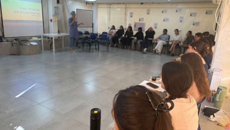 מנחה עומדת ומובילה סדנה קבוצתית במעגל שיח עם משתתפות, כחלק מתהליך למידה והעמקה של הקומה הישראלית
